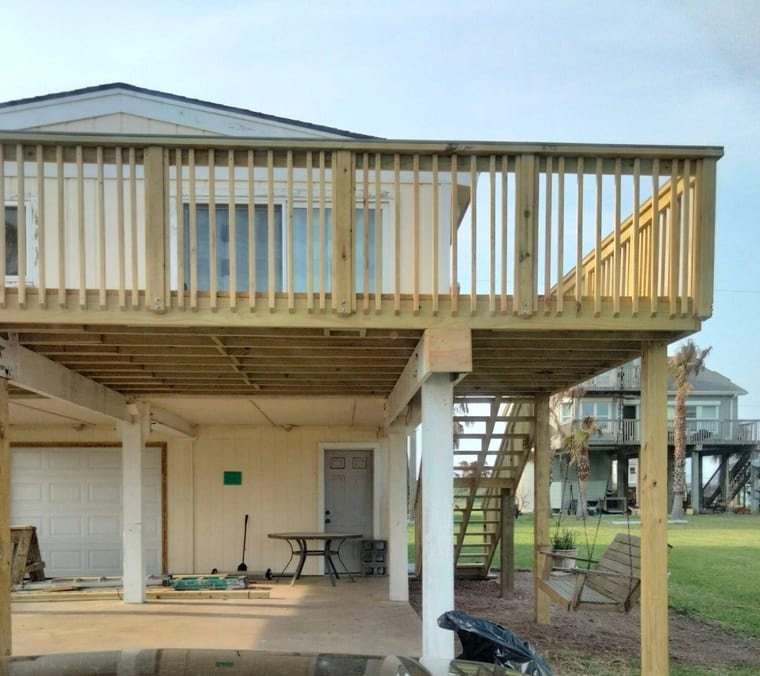 New pressure-treated deck with picket railings on a raised coastal home